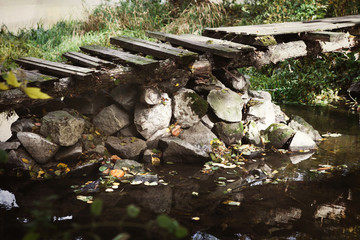 Old abandoned wooden bridge across stream