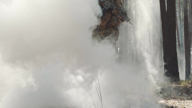 Fully Equipped Soldier comes out of the smoke in the Middle of the Forest