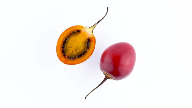 Top view from above of a one and a half of ripe tamarillo fruits. Rotating on the turntable isolated on the white background. Close-up. Macro.