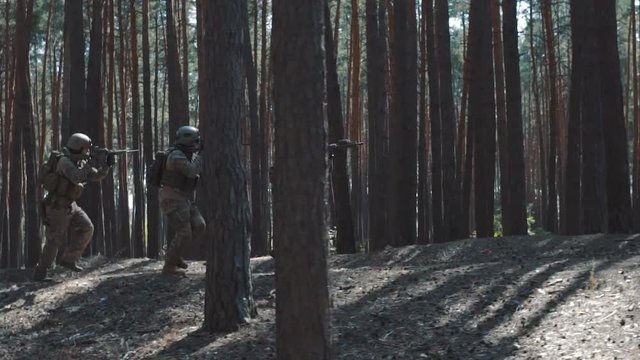 Soldiers of the US Army are running to attack in a smoky forest