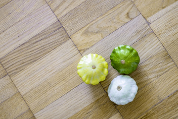 Three small scallop squashes over wooden background top view