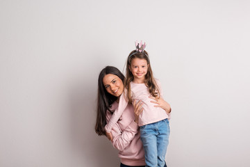 A small girl with crown headband and her mother standing in a studio.