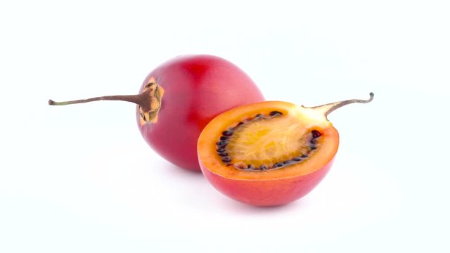 One and a half of ripe tamarillo fruits. Rotating on the turntable isolated on the white background. Close-up. Macro.
