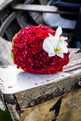 Wedding bouquet on wooden boat, romantic picture on wedding day, bridal bouquet with red peonies and white orchids, in summer
