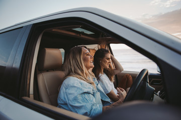 two attractive women driving truck at beach