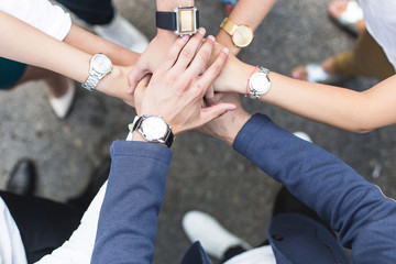 business, people and teamwork concept - smiling group of businesspeople standing in circle and putting hands on top of each other