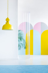 Yellow lamp, colorful wallpaper and plastic tube in a room interior. Real photo