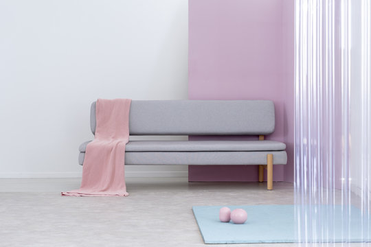 Pink blanket on a modern sofa in a simple living room interior. Real photo. Place your painting