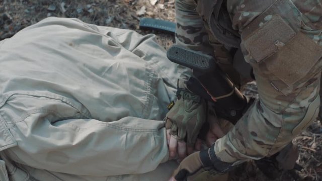 A soldier of the US Army ties the hands of a captive terrorist