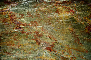 Rock surface structure background in green-gold and copper tones