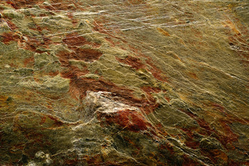 Rock surface structure background in green-gold and copper tones