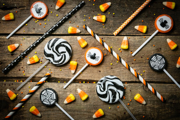 Fototapeta na wymiar Halloween background - candies and lollipops, straws, wood background