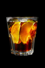 A single-colored transparent cocktail, refreshing in a low glass with radiant ice cubes with taste of berries, cola and slice, lime quartet. Side view Isolated black background