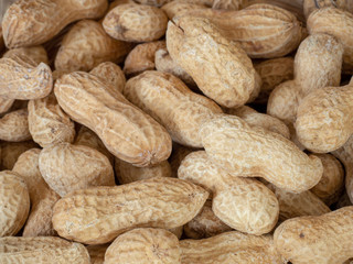 Fototapeta premium Closeup dried peanuts in shells on peanuts background on wooden table. Concept of snack