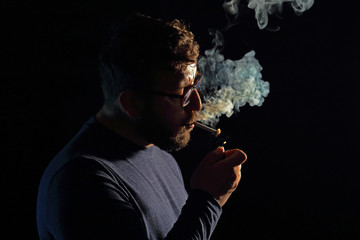 man brunette with a cigarette in the dark, a lot of smoke