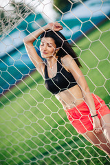 Sport girls in shorts and black top posed near football goal. Sexy young woman do sport exercises in sexy sport wear.