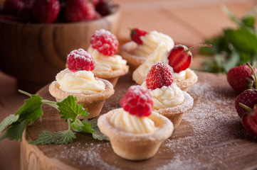Tartlets with cream, raspberries, strawberries.