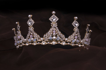 golden crown with pearls and beads isolated on the fabric