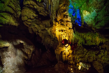 old stalactites on the ceiling of the Prometheus cave in colorful lighting