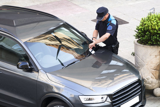 policeman writing fine ticket for car bad parking