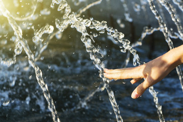Obraz na płótnie Canvas Hand of a girl in a spray of water from a fountain.