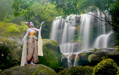 Beautiful woman wearing traditional thai dress with thai style in beautiful water fall in neture.