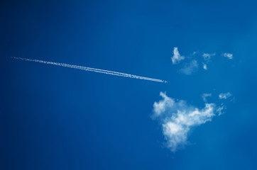 Vector illustration of an airplane with a tail far in the clouds against a background of clear sky