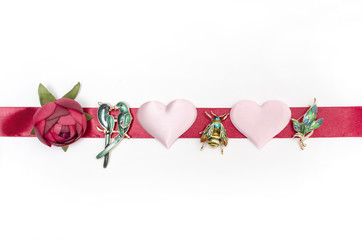Composition with brooches, hearts, rose and ribbon on a white background