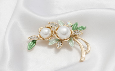 gold brooch flower with pearl on silk background