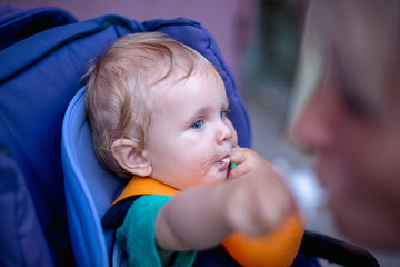 A small cute baby eats in a baby stroller