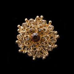 gold round brooch with diamonds isolated on black