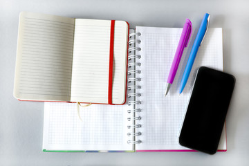 open notebooks, pens and smartphone on a gray background