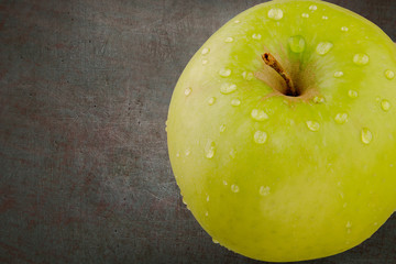 Green aple with water drops.  Top view with copy space on dark background.