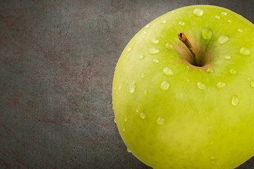 Green aple with water drops.  Top view with copy space on dark background.
