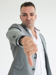 Cheerful handsome businessman in grey suit showing thumbs down negative gesture sign to dislike or...