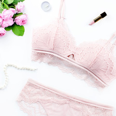 Woman elegant pink lace bra and panties, flowers, jewelry. Stylish lingerie flat lay. Underwear fashion concept