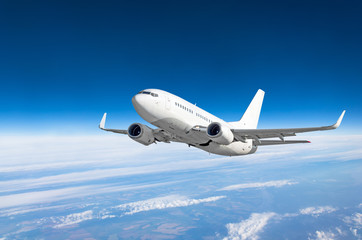 Obraz premium Samolot pasażerski leci wysoko nad chmurami i błękitnym niebem.