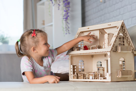 A Girl Playing With A Dollhouse