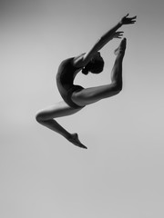 Flexible girl in black body in a jump
