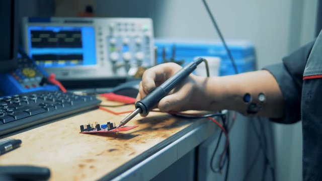 Close up of a microchip getting brazed by a worker with prosthetic hands