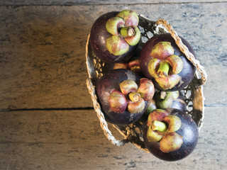 Mangosteen is placed in a basket on a wooden table.