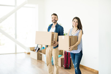 Fototapeta na wymiar Happy Couple Carrying Cardboard Boxes In New Home