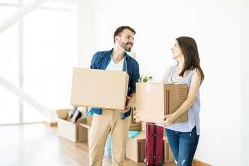 Smiling Man And Woman Carrying Boxes In New House