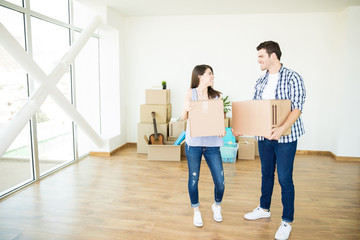 Fototapeta na wymiar Couple Carrying Belongings In Moving Boxes In New Luxury House