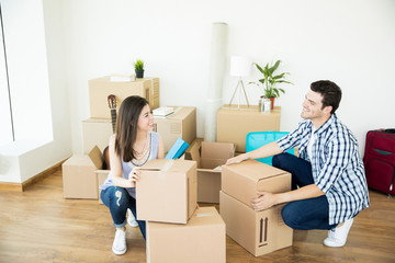 Couple Crouching While Stacking Cardboard Boxes In New Home