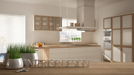 Wooden table, desk or shelf with potted grass plant, house keys and 3D letters making the words interior design, over blurred modern kitchen, project concept copy space background