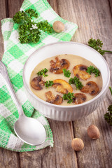 Mushroom cream soup in ceramic bowl on rustic wooden background