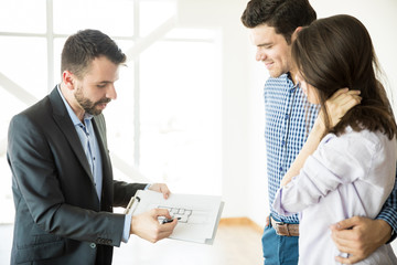 Realtor Showing Blueprint To Couple In New Apartment