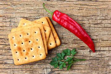 Crackers, hot pepper and parsley on a wooden background. © osoznaniejizni