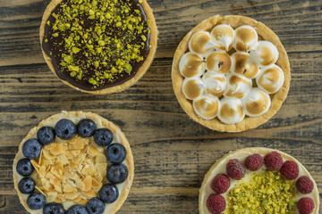 Mini tarts with different filling on rustic wooden black table
